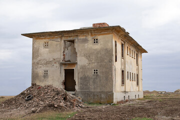 Old ruined and abandoned building and pile of rubble debris, gloomy day light