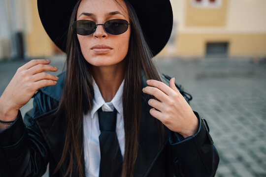 Stylish woman wearing hat, sunglasses and tie posing outdoors - Powered by Adobe