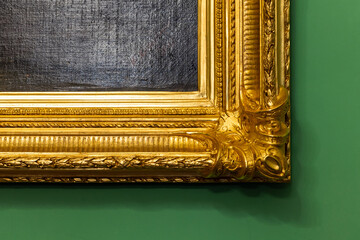 Corner of a vintage golden frame is on green wall, wooden carving