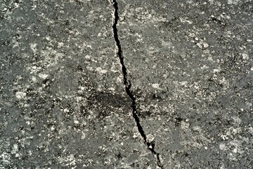 Obraz premium A close-up of a large crack in a gray asphalt surface.