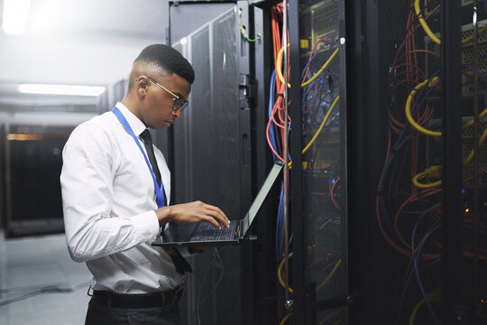 Black man, engineer and server room with laptop for network repair, hardware or storage at data center. Male person, IT technician and computer for technical issue, internet service or system backup