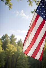 An American flag waving in the wind against a blurred natural background with trees