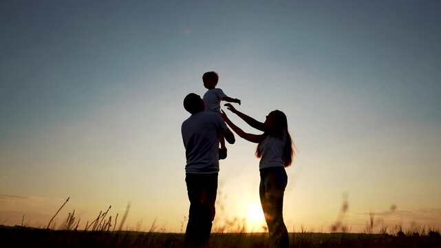 family standing on the field. happy childhood concept for little child. big happy family stands on field, parents raised the child in lifestyle their arms, sunset on the background, silhouettes