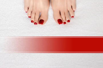 Female toes with red glossy pedicure on white terry towel and red gradient blank for the inscription, close up.