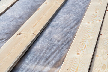 Aligned wooden planks over vapor barrier insulation during energy-efficient wooden house construction