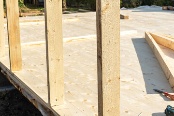 Construction of a wooden frame house with vertical beams on a wooden floor