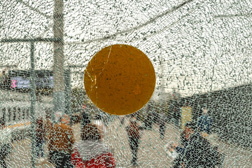 Shattered glass with yellow marker against urban background, blurred figures and architecture create dynamic atmosphere