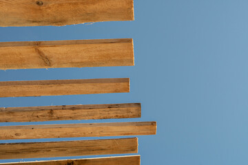 View from below of wooden roof sheathing beams of a frame house against clear sky