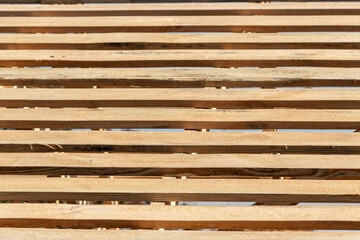 Rows of wooden roof sheathing beams with gaps revealing blue sky