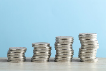 Stacked coins on wooden table against light blue background, closeup. Salary concept