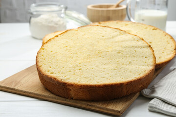 Delicious cut sponge cake on white wooden table