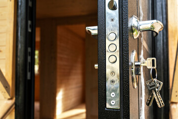 Close-up of lock with keys in door of new wooden house, concept of security and new beginning