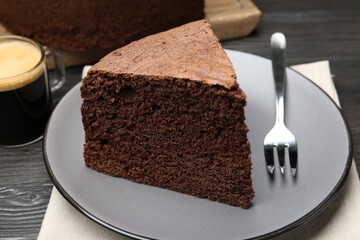 Piece of tasty chocolate sponge cake served on wooden table, closeup