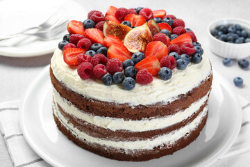 Delicious chocolate sponge cake with berries served on light table, closeup