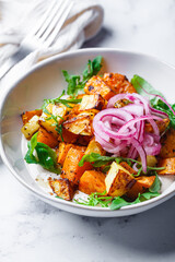 Baked potato and sweet potato wedges with hummus and pickled red onion.