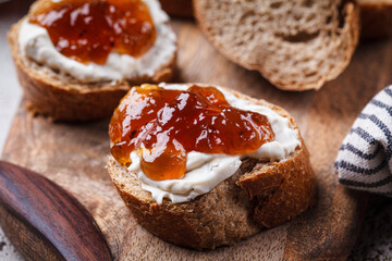 Onion jam on toast with cream cheese, gray background.