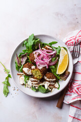 Falafel salad with tahini, red pickled onions and nuts.