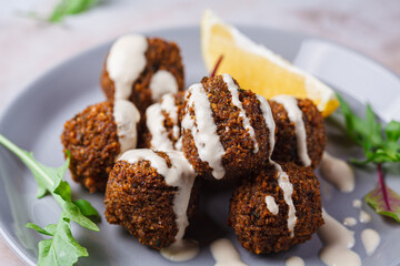 Falafel balls with tahini on gray plate. Israeli cuisine concept.