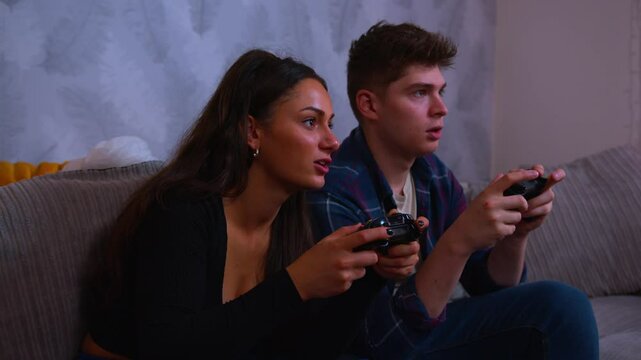 Cute couple playing video games intensely both of them win and celebrate together joyously