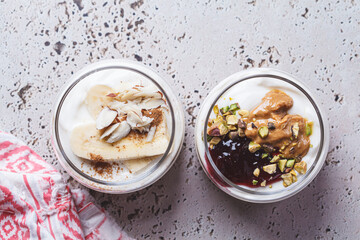 Overnight oatmeal with peanut butter, banana, nuts and jam in jars.