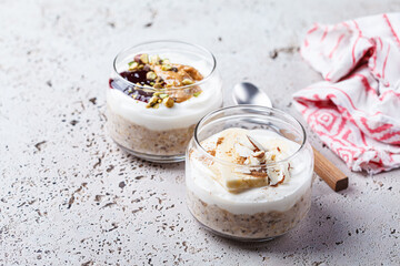 Overnight oatmeal with peanut butter, banana, nuts and jam in jars.