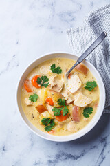 Chicken breast stew with potatoes and carrots in white bowl. Comfort food concept.