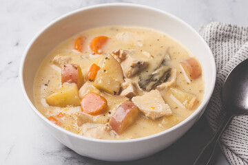 Chicken breast stew with potatoes and carrots in white bowl. Comfort food concept.