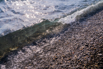 Water sea beach. Wave ocean blue. Stone texture reflection sun. Surface coast pebbles. 