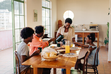 Mature mom serving a delicious breakfast for her family at the kitchen table