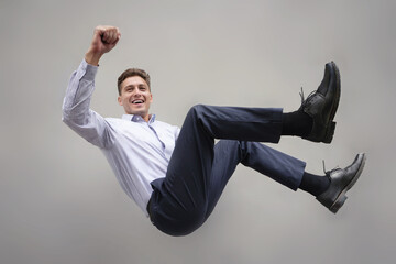 Cheerful businessman is hanging and floating in the air.