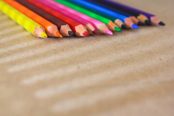 Colored pencils neatly arranged in a row, displaying a vibrant spectrum of colors on a brown surface. Perfect for themes related to art, education, and creativity.