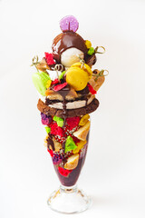 Delicious huge dessert with raspberries, whipped cream, chocolate, caramel and meringue, serving of Eton mess, arranged in a glass.