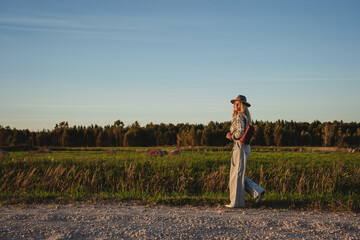 Fashionable woman walks along a gravel road in a rural setting