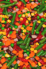 Sliced vegetables, corn, beans, peas, carrots, sweet peppers background.