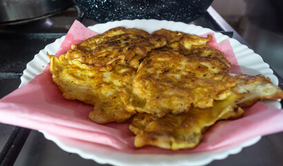 Chicken chops on a white plate on a gas stove. Fried chicken meat in breading