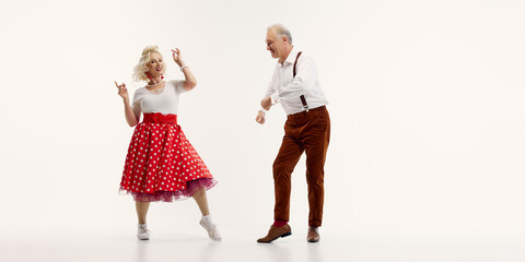 Elderly man and woman share joyful dance in retro-inspired outfits isolated on white background....