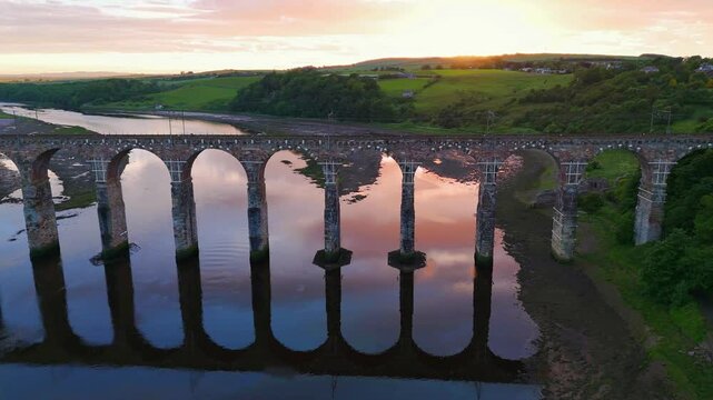 Berwick, Northumberland, UK, June 19, 2024; sunset high level panning aerial clip with train of the Royal Border Bridge Viaduct, Berwick, Berwick-upon-Tweed, Northumberland, England, UK.