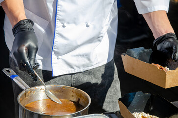 Close-up of prepared food placed in containers at an outdoor open kitchen