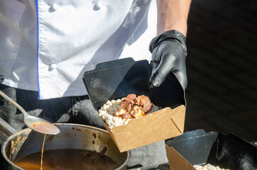 Close-up of prepared food placed in containers at an outdoor open kitchen