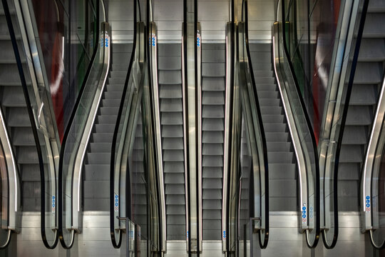 A captivating image showcasing the symmetry of modern escalators, mirroring each other in a well-lit setting, representing progress and urban architecture. - Powered by Adobe