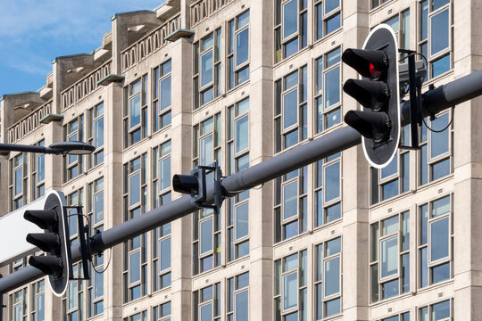 A close-up view of traffic lights in front of a modern office building, capturing the elements of city infrastructure and architecture on a sunny day.