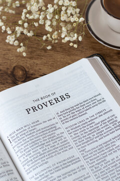 Proverbs open holy bible book with cup of coffee on wooden table. Wisdom from God Jesus Christ, studying Old Testament Scripture, biblical concept.