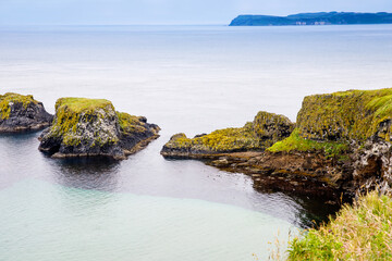 Coast near Carrick-a-Rede Rope Bridge, famous rope bridge near Ballintoy in County Antrim, Northern Ireland on Irish coastline. Wild Atlantic Way on cloudy day.