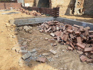 A construction site featuring rubble and bricks scattered around partial walls, indicating a...