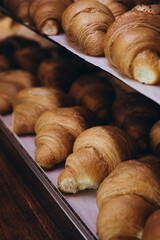 Delicious croissants on the store showcase of the bakery house, close up.