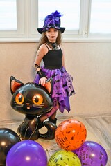 A beautiful little witch, a girl in a beautiful festive outfit for Halloween, came for her candy.