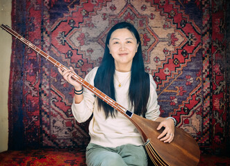 Chinese women playing the Dombra instrument in a Uyghur-style room in Kucha, Xinjiang.
