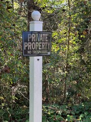 Private property no trespassing sign on a white post