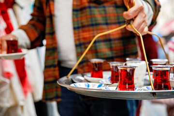 Turkish tea in traditional glass mugs on a metal tray. Street vendor selling hot tea in Istanbul, Turkey, Grand Bazaar.