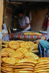 A close-up of Xinjiang's local specialty roast naan in Uyghur style, with staff in the background making naan in a shop, in Kashgar Old City, Xinjiang, China